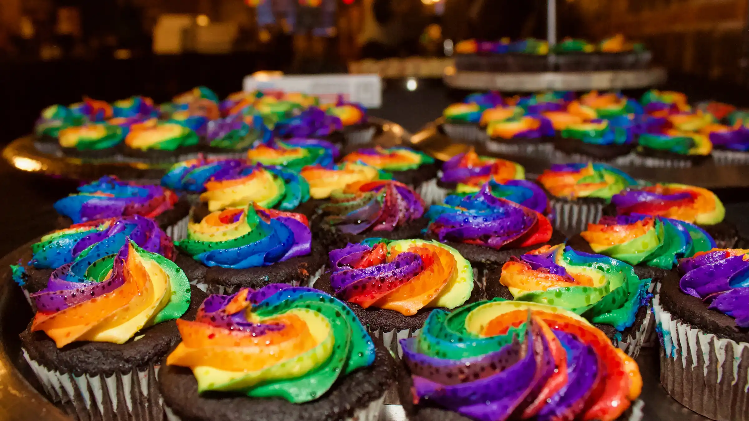 Dozens of rainbow frosted chocolate cupcakes.